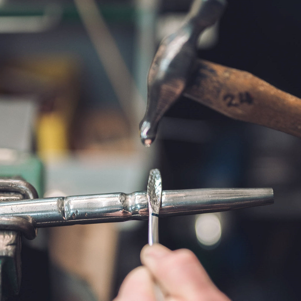 Person using a tool to make a silver bangle